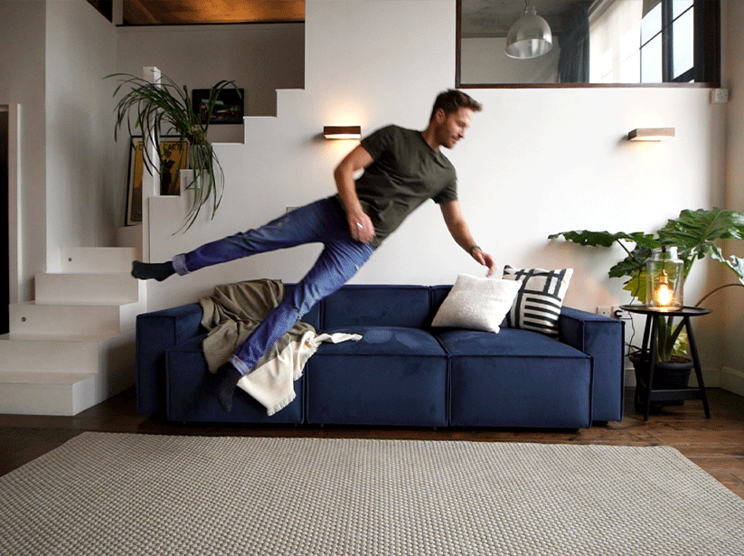 Man jumping onto Model 03 3 Seater in Teal Velvet