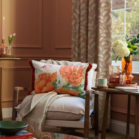 A living room decorated with spring and summer decor, including a patterned cushion with a red floral design.