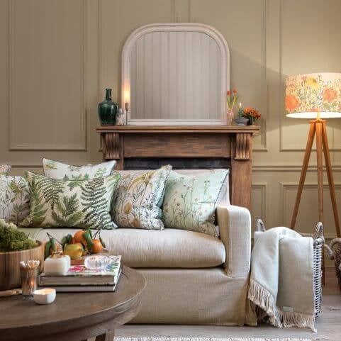 A living room sofa decorated with a series of colourful botanical cushions and other summer decor.