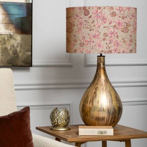 A luxurious table lamp with a glass base and summer decor lamp shade decorated with a colourful posy design. 