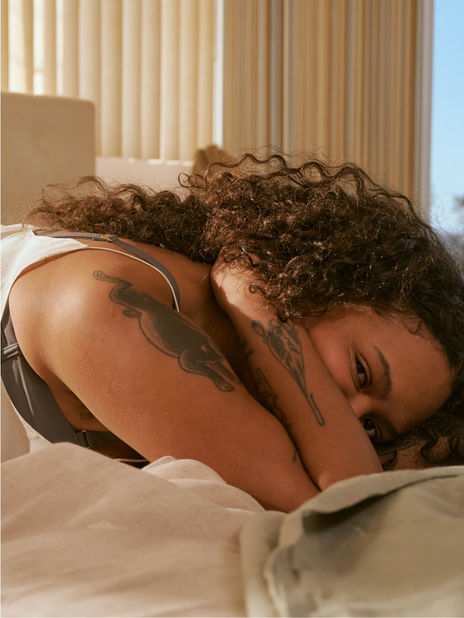 Profile view of a woman laying down on her stomach covering her mouth with her elbow