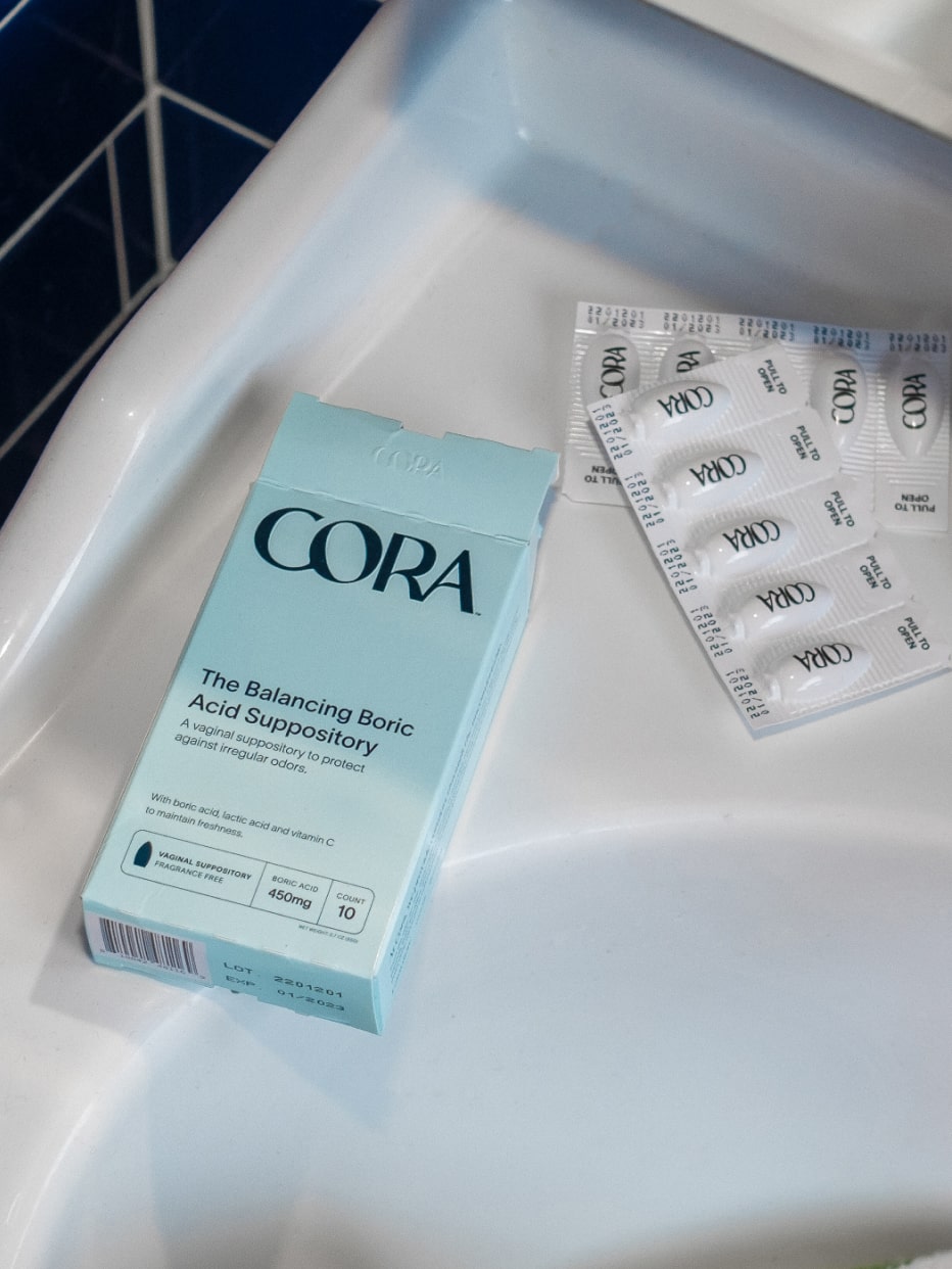The Cora Boric Acid Suppository packaging and capsule product sitting on a bathroom sink