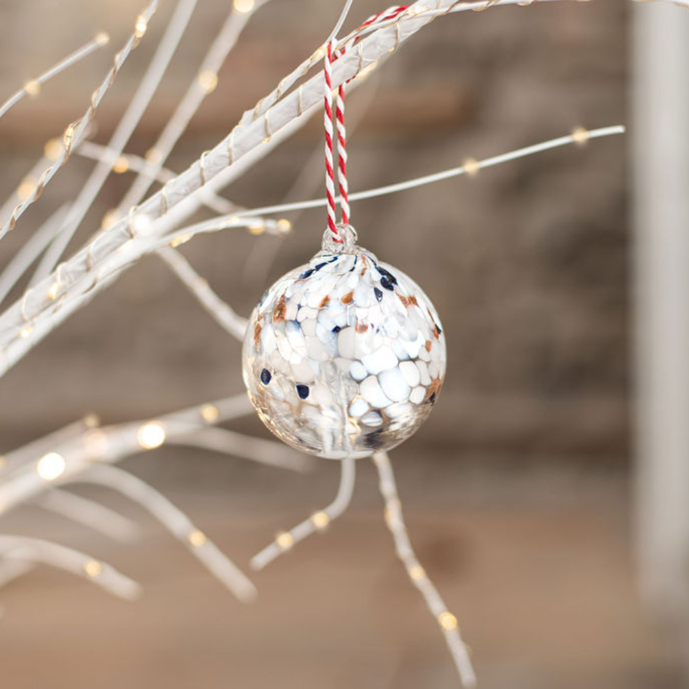 2" Tree of Peace hanging from white branches with twinkle lights. 
