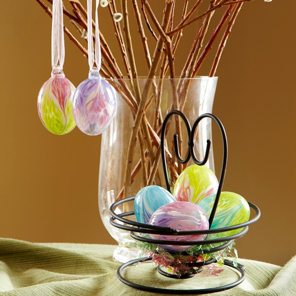 Oval Glass Orbs with pastel colours on an egg tree and in a wire basket with a heart. 