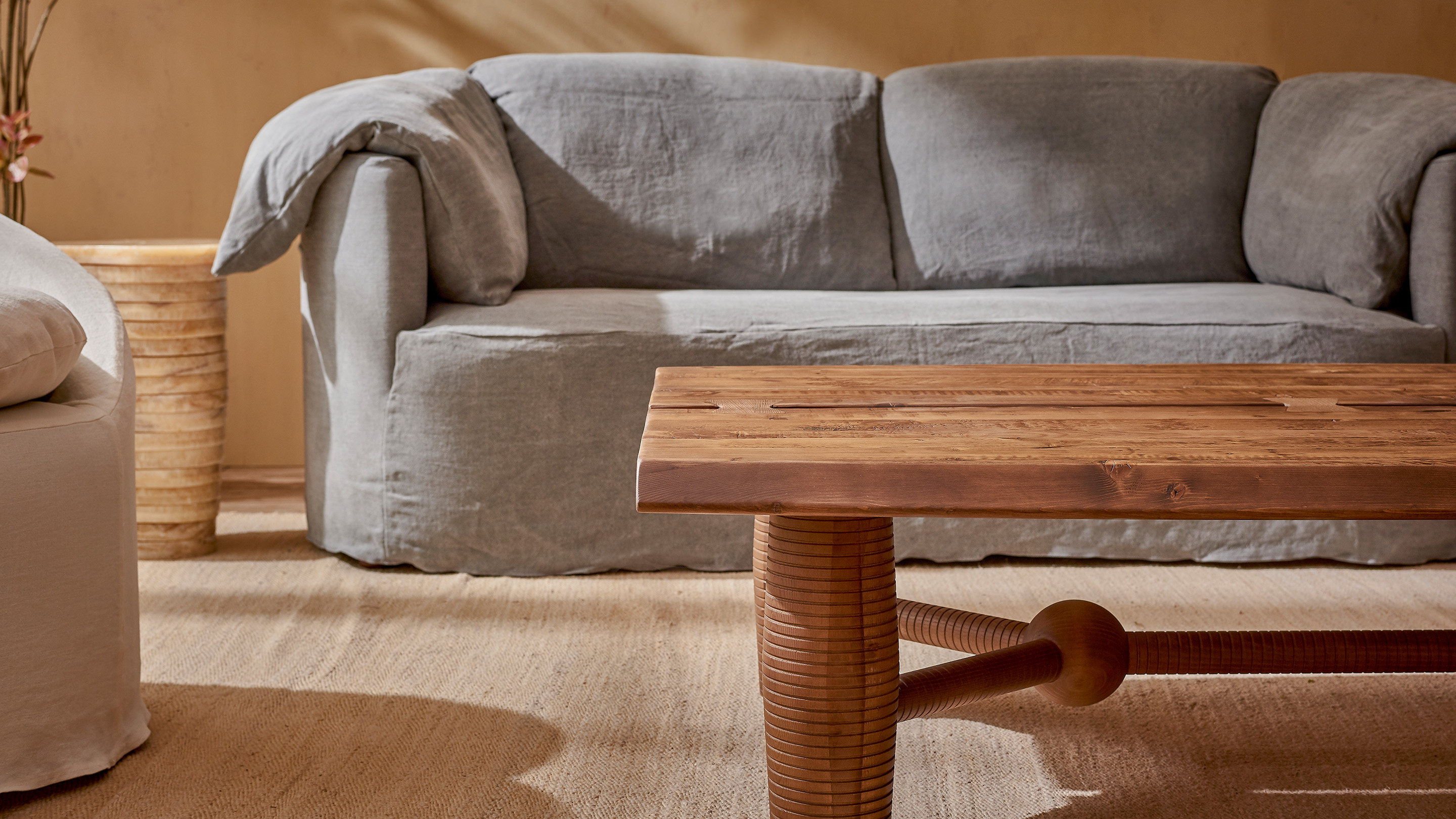 Zenia Coffee Table in Heritage Pine, a medium, bosc pear shade with earthy undertones, placed in front of the Loula Sofa