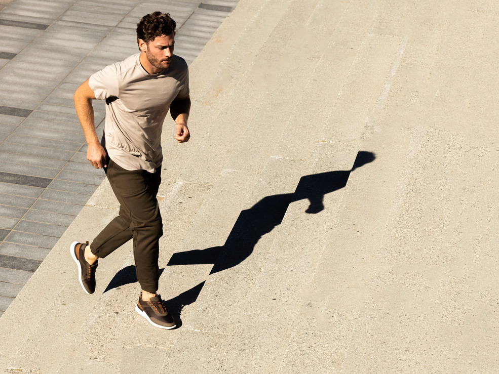 Full body view of a man running up steps wearing Crossover Trainer WTZ in Brown