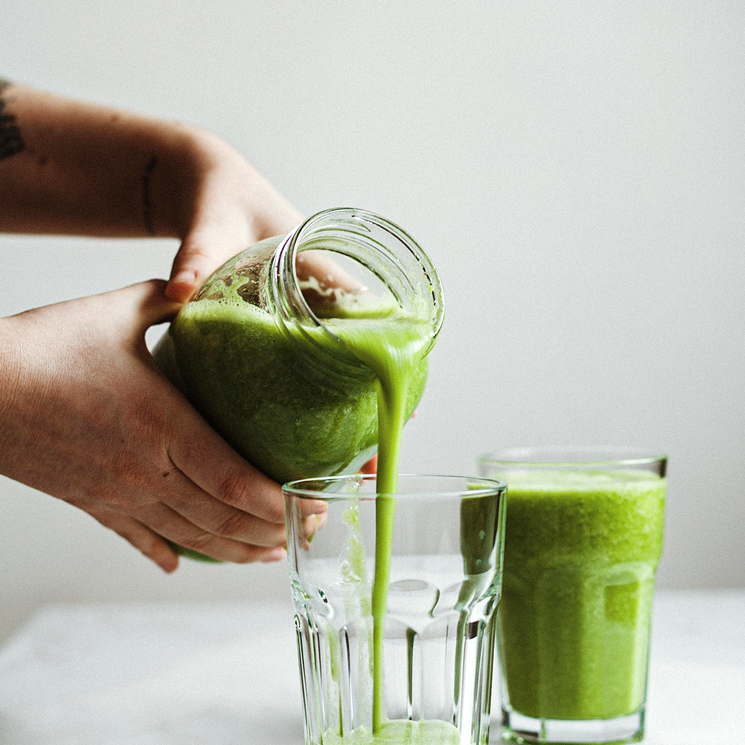 green smoothie being poured into a glass 