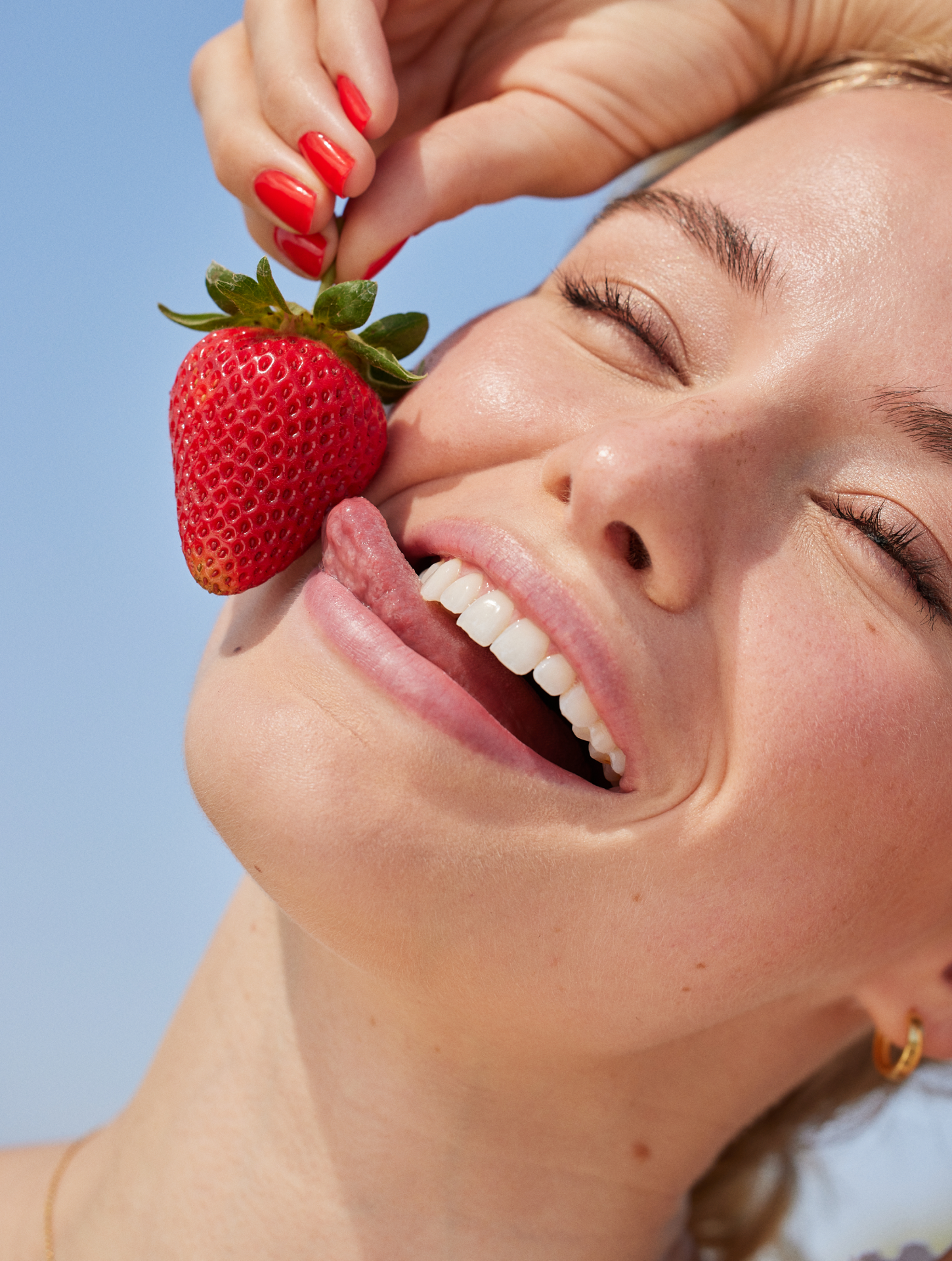 Girl holding strawberry and smiling joyfully 