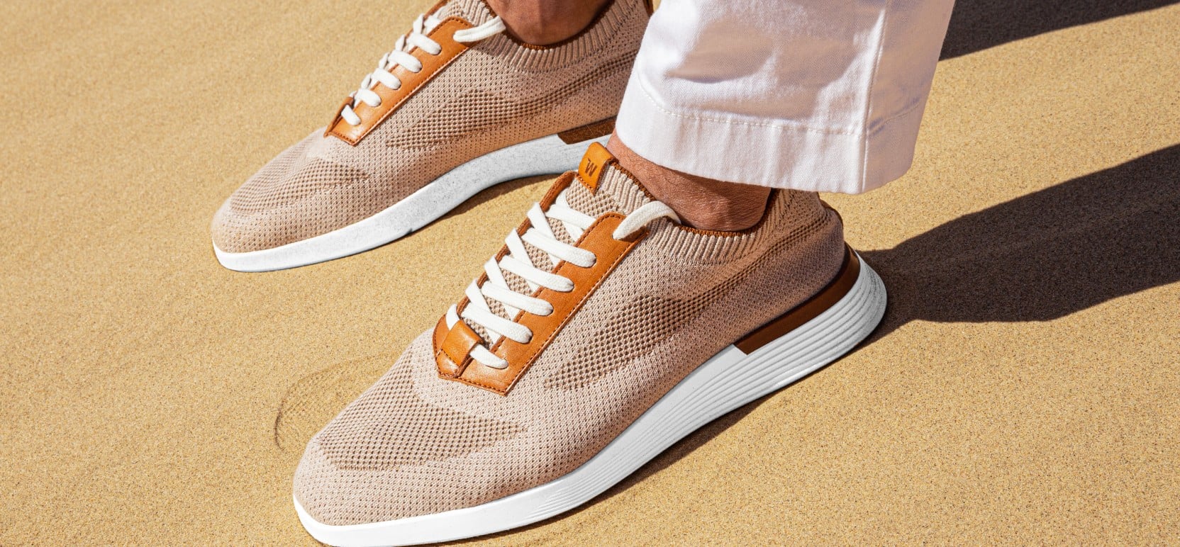 Ankle down view of supremeknit trainer mocha with a sand background