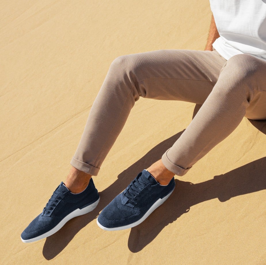 Waist down view of supremeknit trainer navy with a sand background