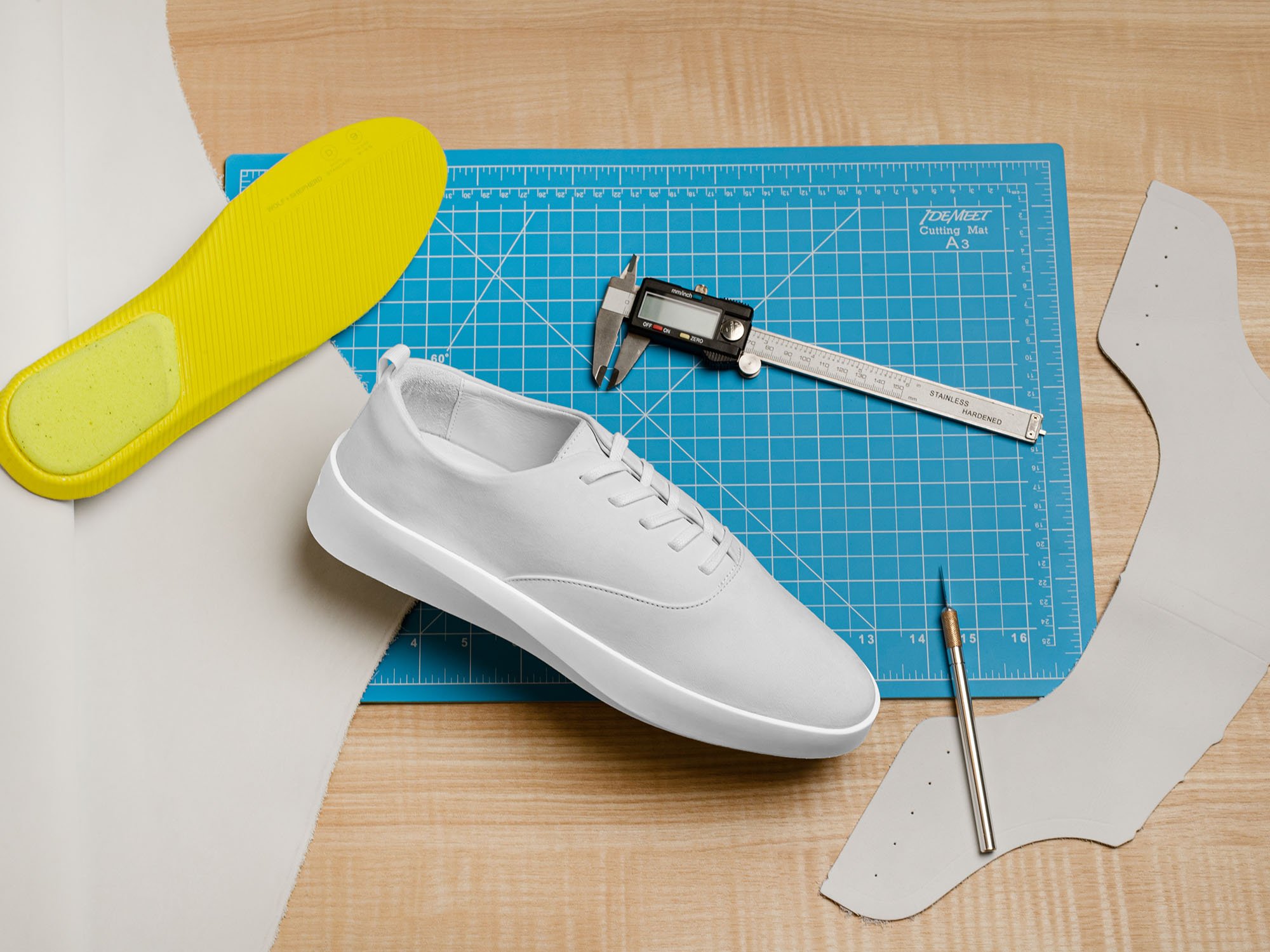 Overhead view of cruise lace up in white, footbed, and ruler on a cutting board