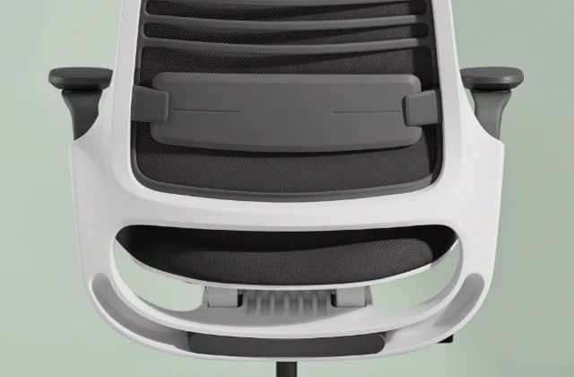 Silla de oficina Steelcase Serie 1 en negro, mirando hacia atrás, mostrando el apoyo lumbar, sobre fondo verde.