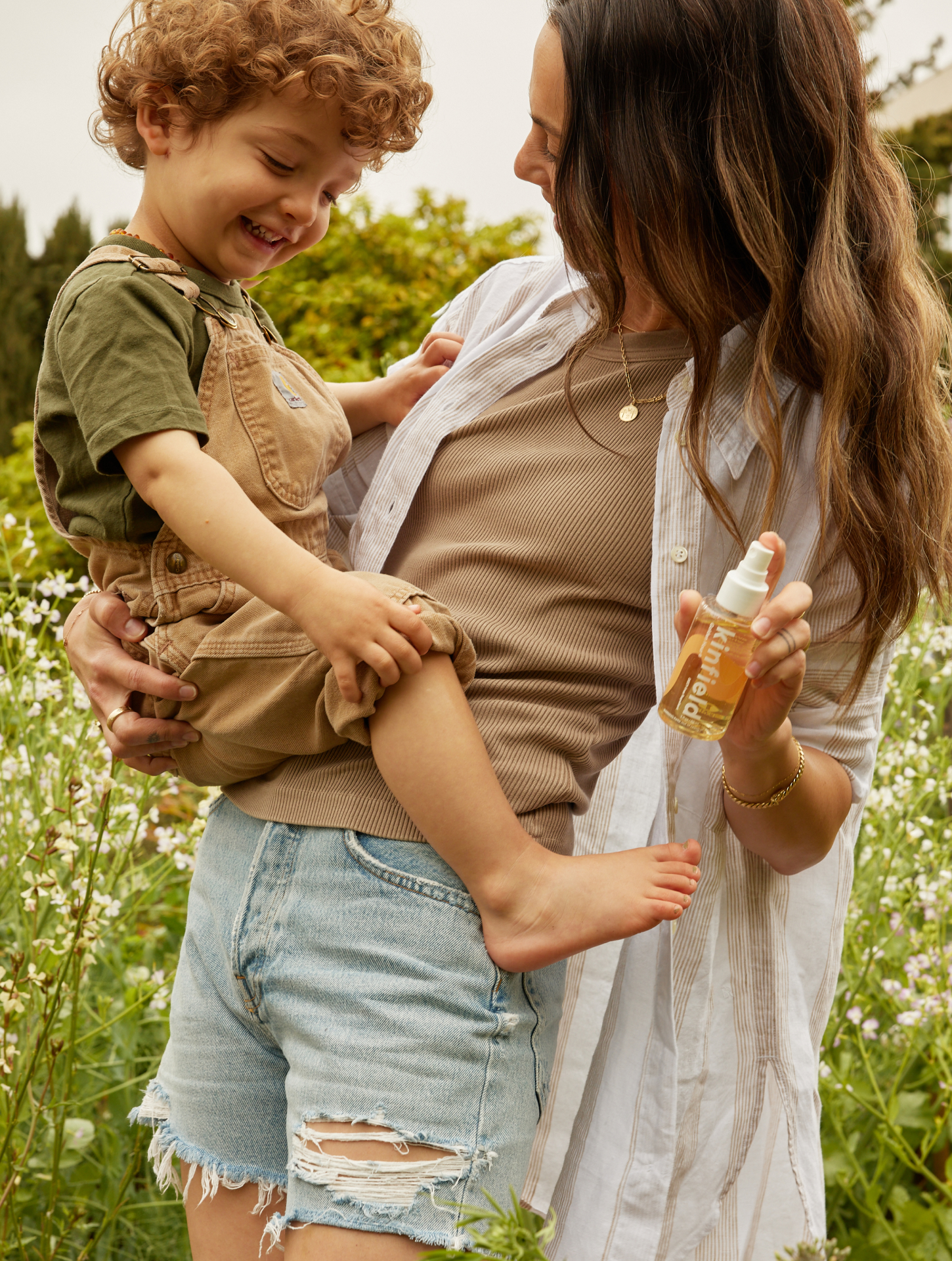 woman with her childen in a garden with bug repellent spray