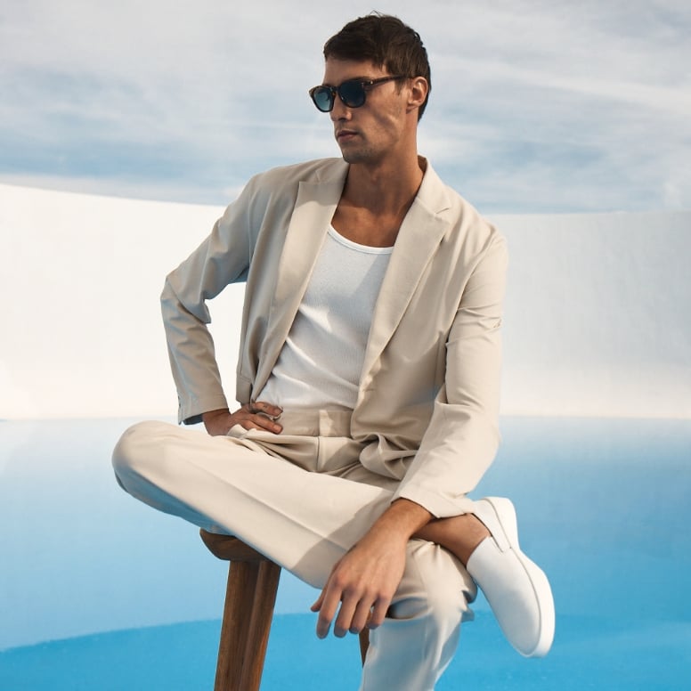 Man sitting wearing Men's Shoe Cruise Slip on in White , white background and blue floor