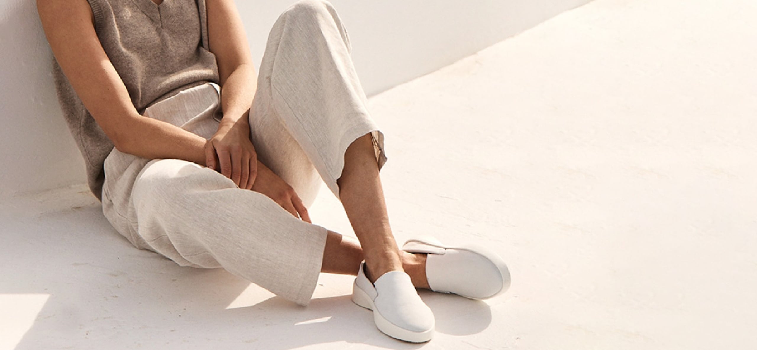 Neck down view of Woman Sitting wearing Women's Shoe Cruise Slip On in White .
