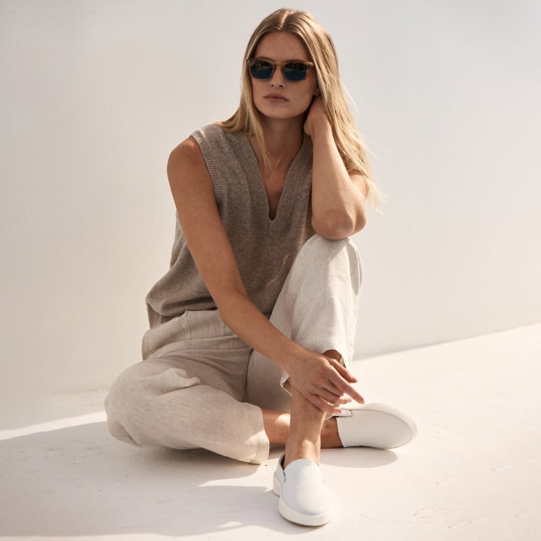 Full body view of a woman sitting wearing Women's Shoe Cruise Slip On in White .