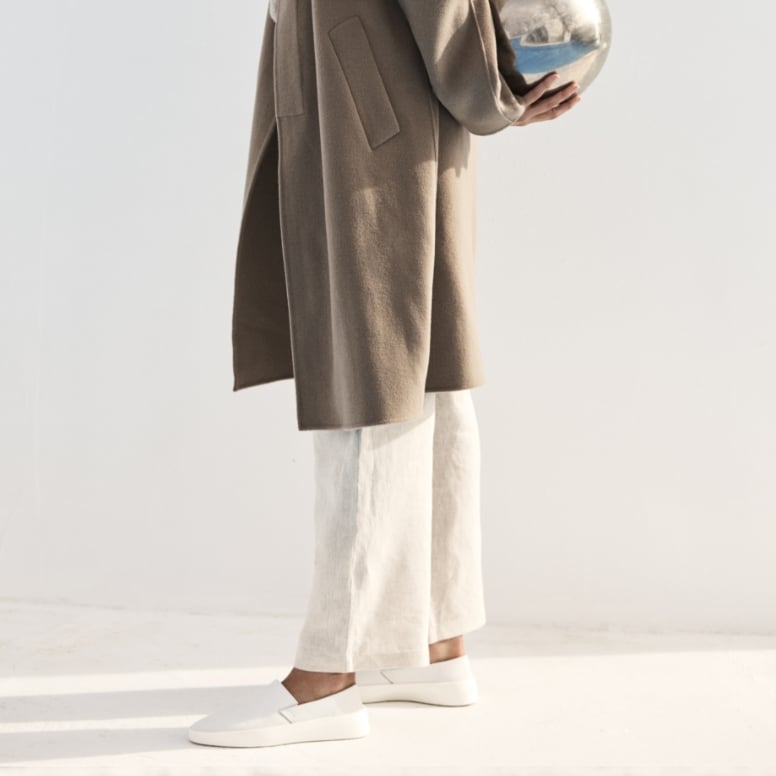 Shoulder down view of woman standing holding a mirror ball wearing Women's Shoe Cruise Slip On in White