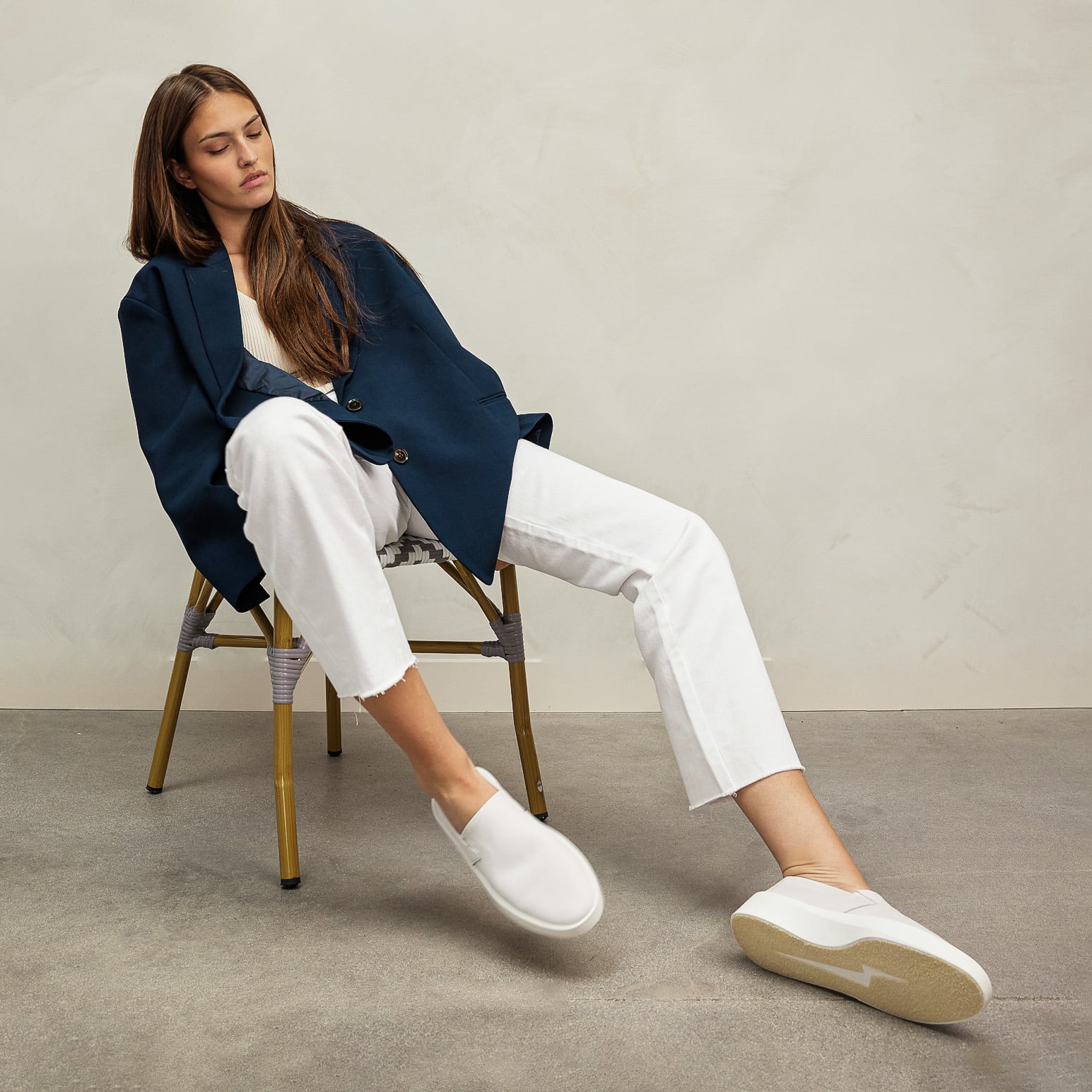 Full body view of Woman sitting on chair wearing Women's Shoe Cruise Slip On in White