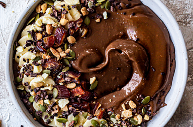 A cacao smoothie bowl with various superfood toppings including cacao nibs