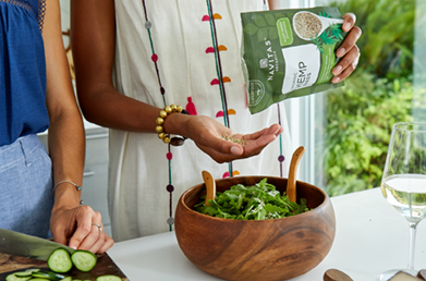A woman sprinkling hemp seeds on a salad