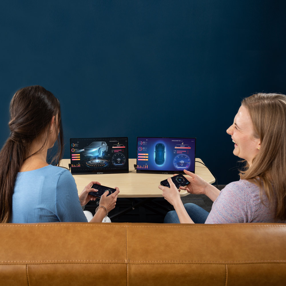 SideTrak Solo HD Triple two women sitting on a couch having fun and laughing while using screens with a gaming system