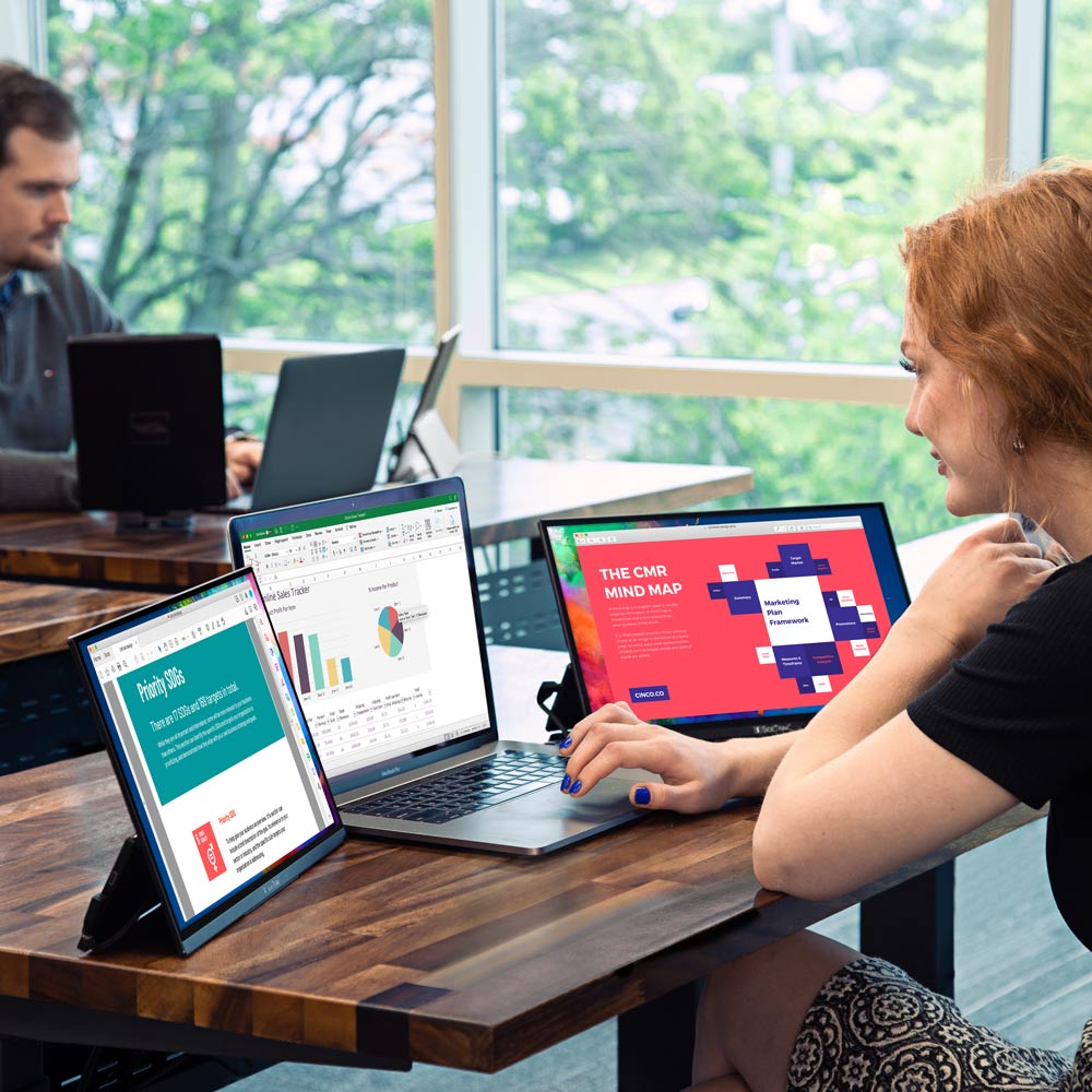 SideTrak Solo HD Triple woman sitting at desk in office setting working on triple screen setup