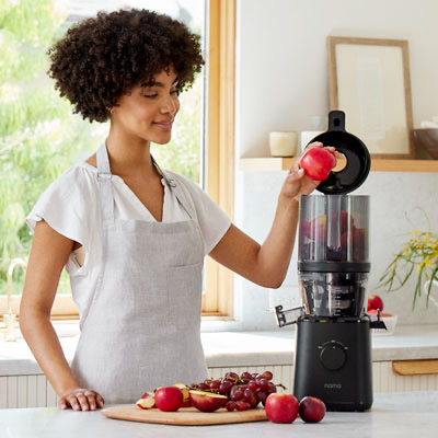 a person pouring juice from a Nama J2 juicer into a glass