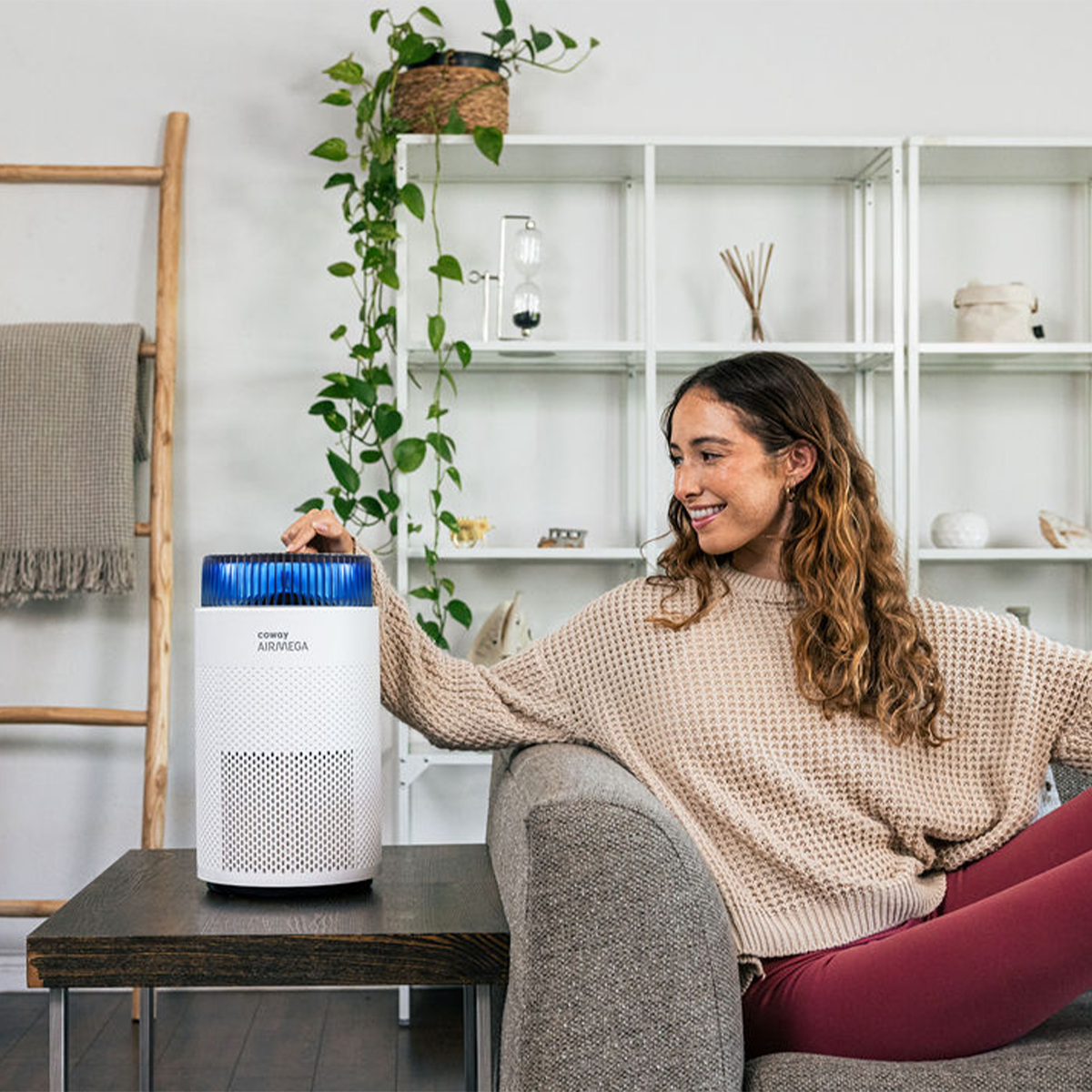 A woman is operating the Airmega 100 on the sofa