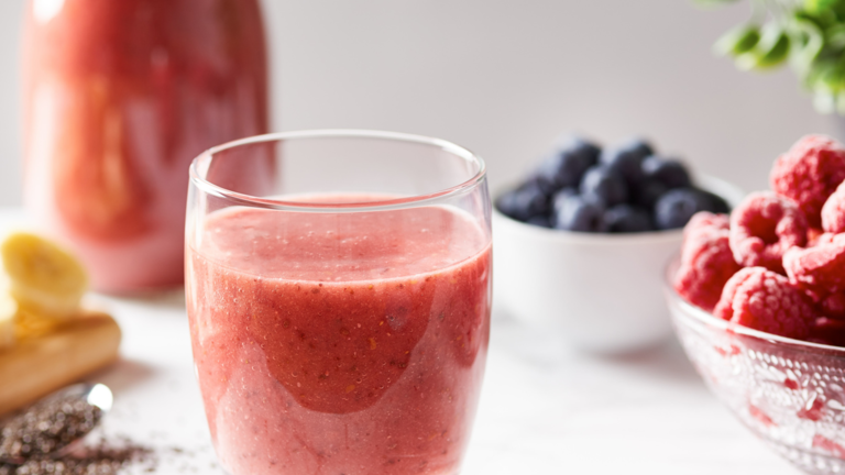 berry smoothie in glass with fruit bowls 