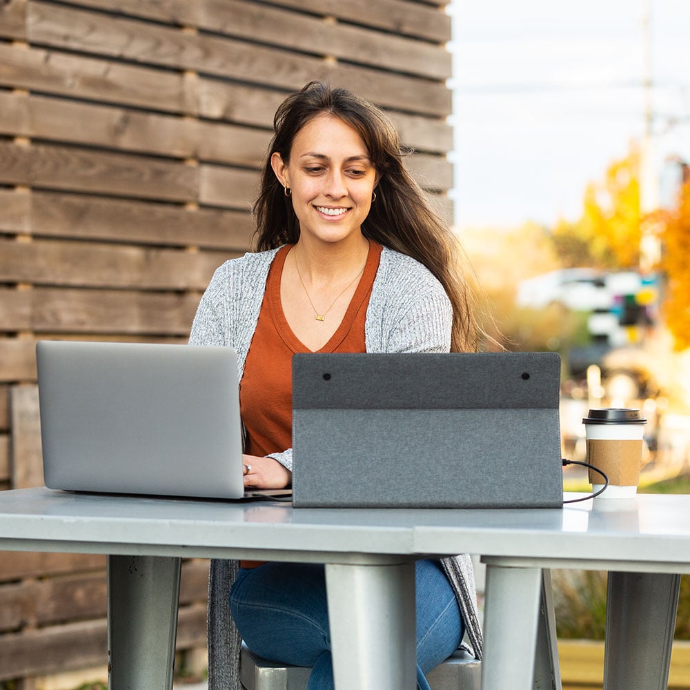Solo Econ SideTrak Travel Monitor woman using a sidetrak solo travel monitor with a laptop for a dual screen set up