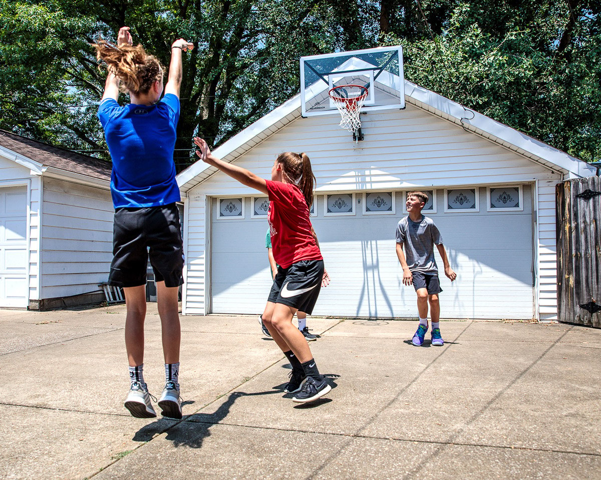 Athletes playing in the driveway on a Silverback Wall-Mounted Basketball Hoop