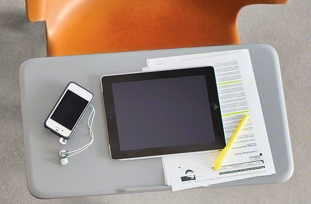 Silla Steelcase Node de color naranja, centrada en la superficie de trabajo, sobre fondo gris