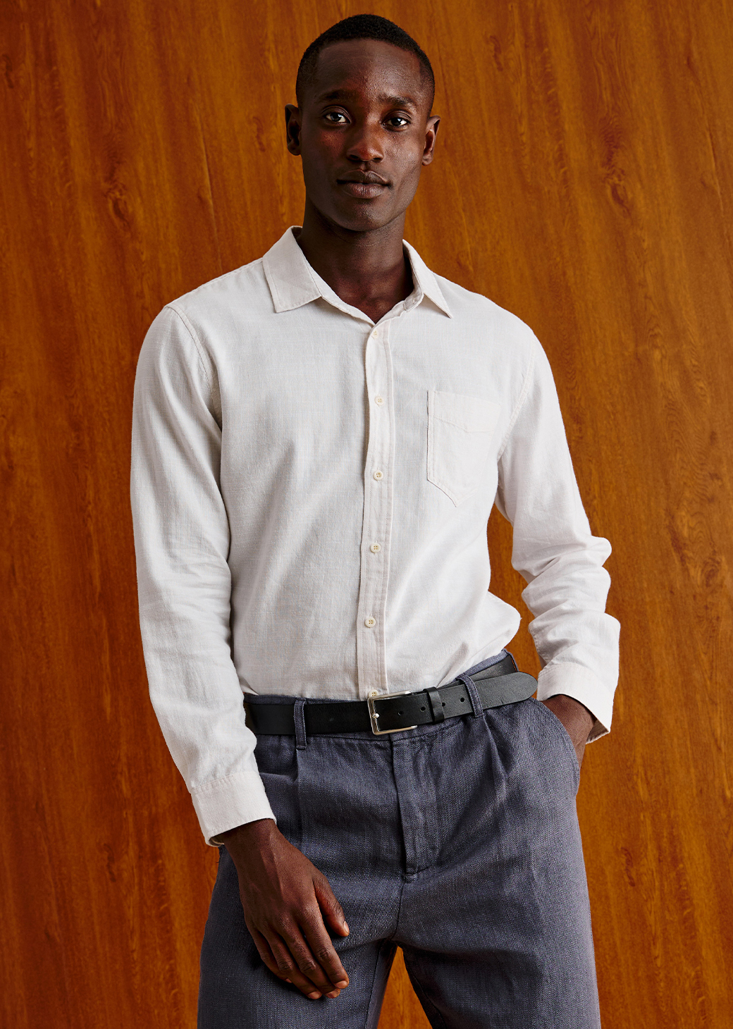 Man wearing a white long sleeve shirt against a brown background.