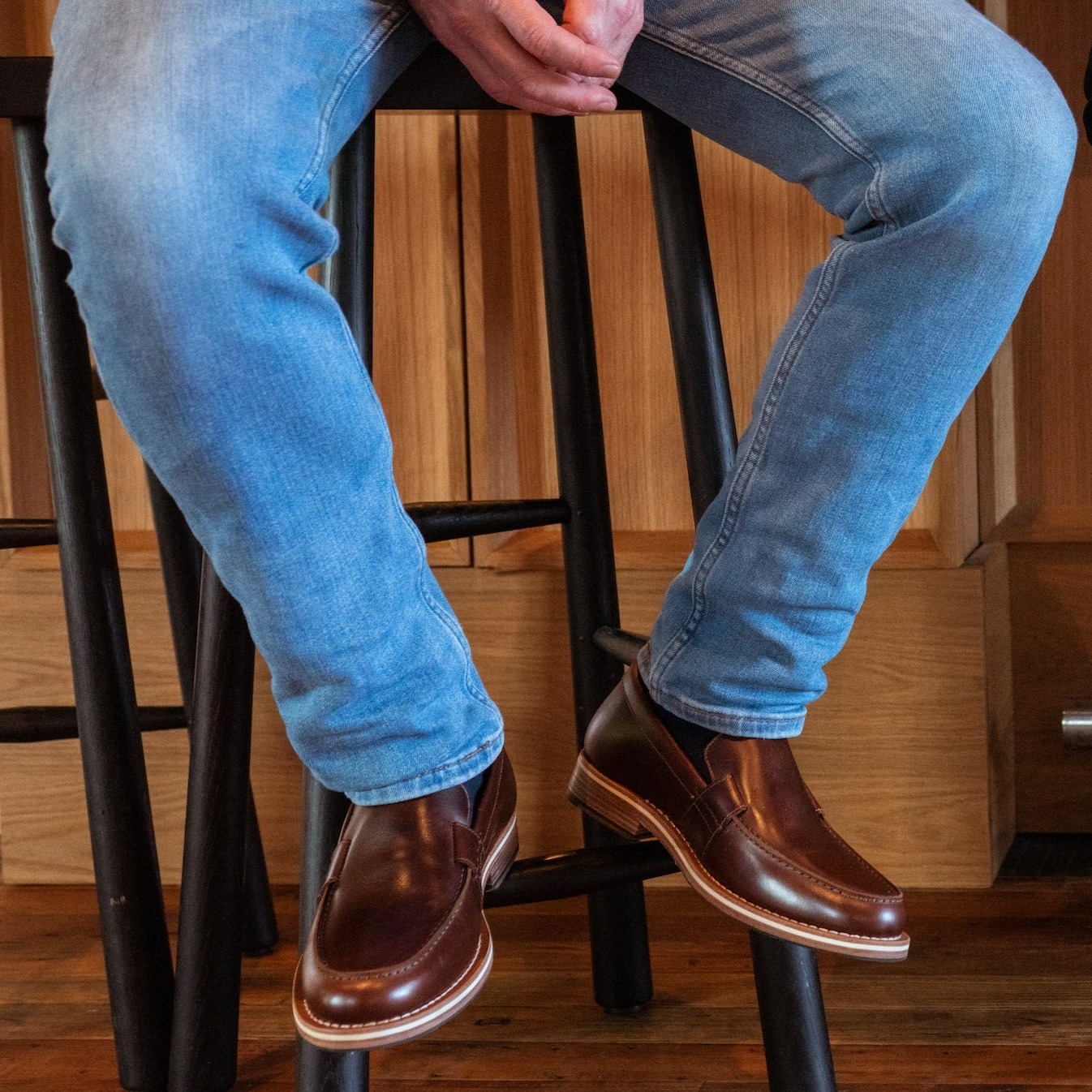 HELM - Man wearing Wilson Brown and jeans sitting on stool