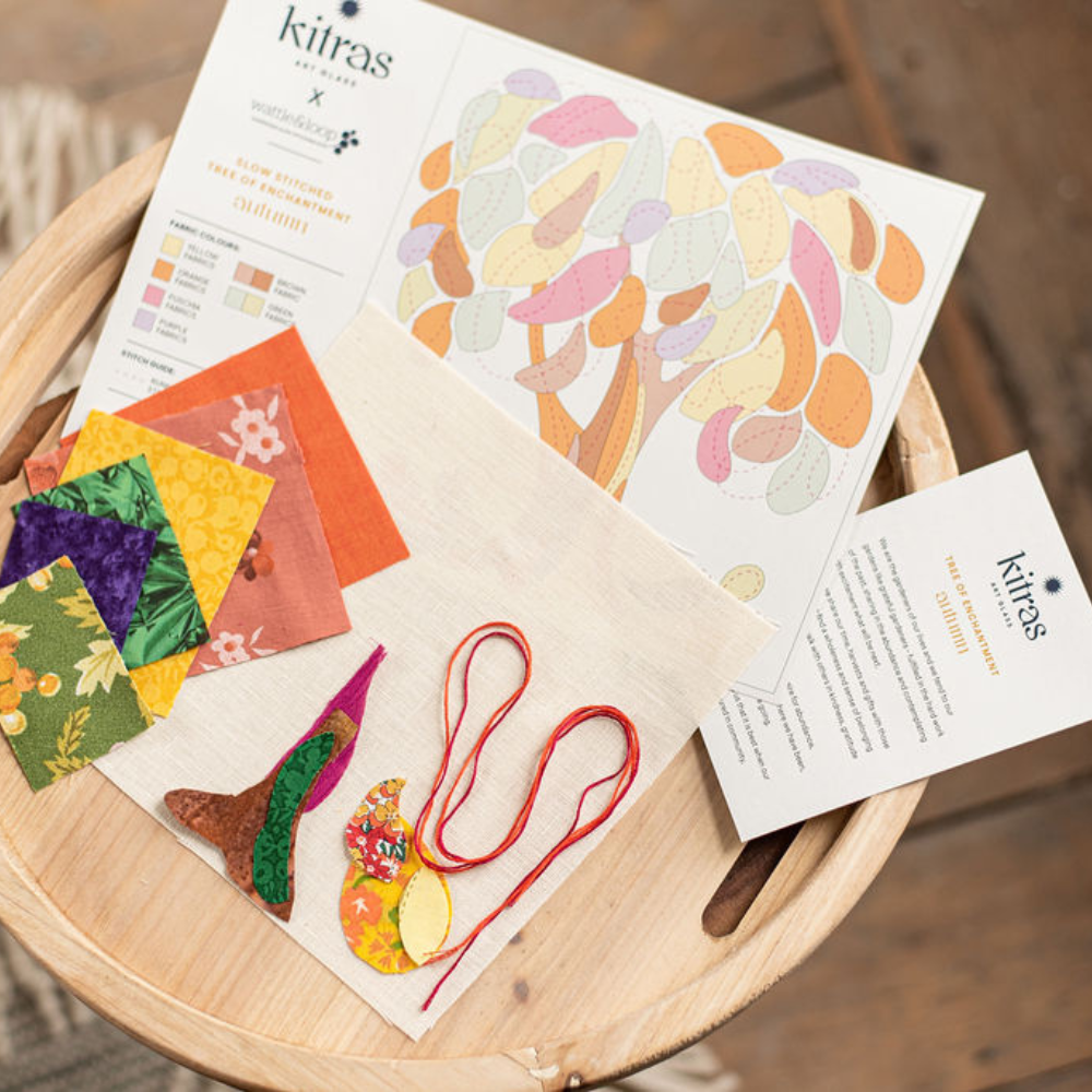 orange, brown, cranberry, yellow, green and blue fabrics and threads on a wooden tray with slow stitch pattern in background on a wood floor