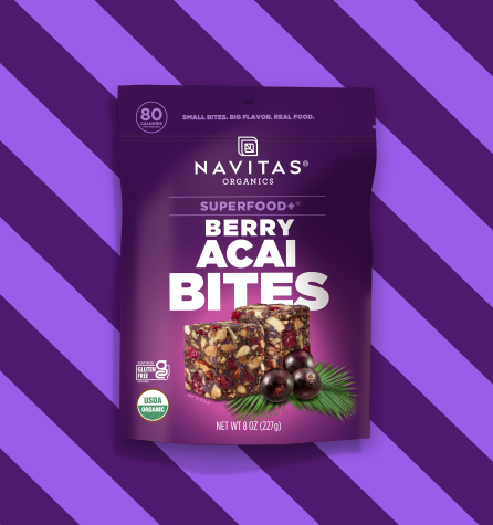 A package of Navitas Organics Superfood+ Berry Acai BITES against a two-toned purple striped background.