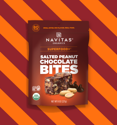 A package of Navitas Organics Salted Peanut Chocolate BITES against a two-toned brown striped background.