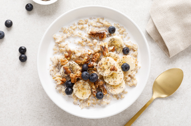 A bowl of oatmeal topped with fruit, nuts and seeds.