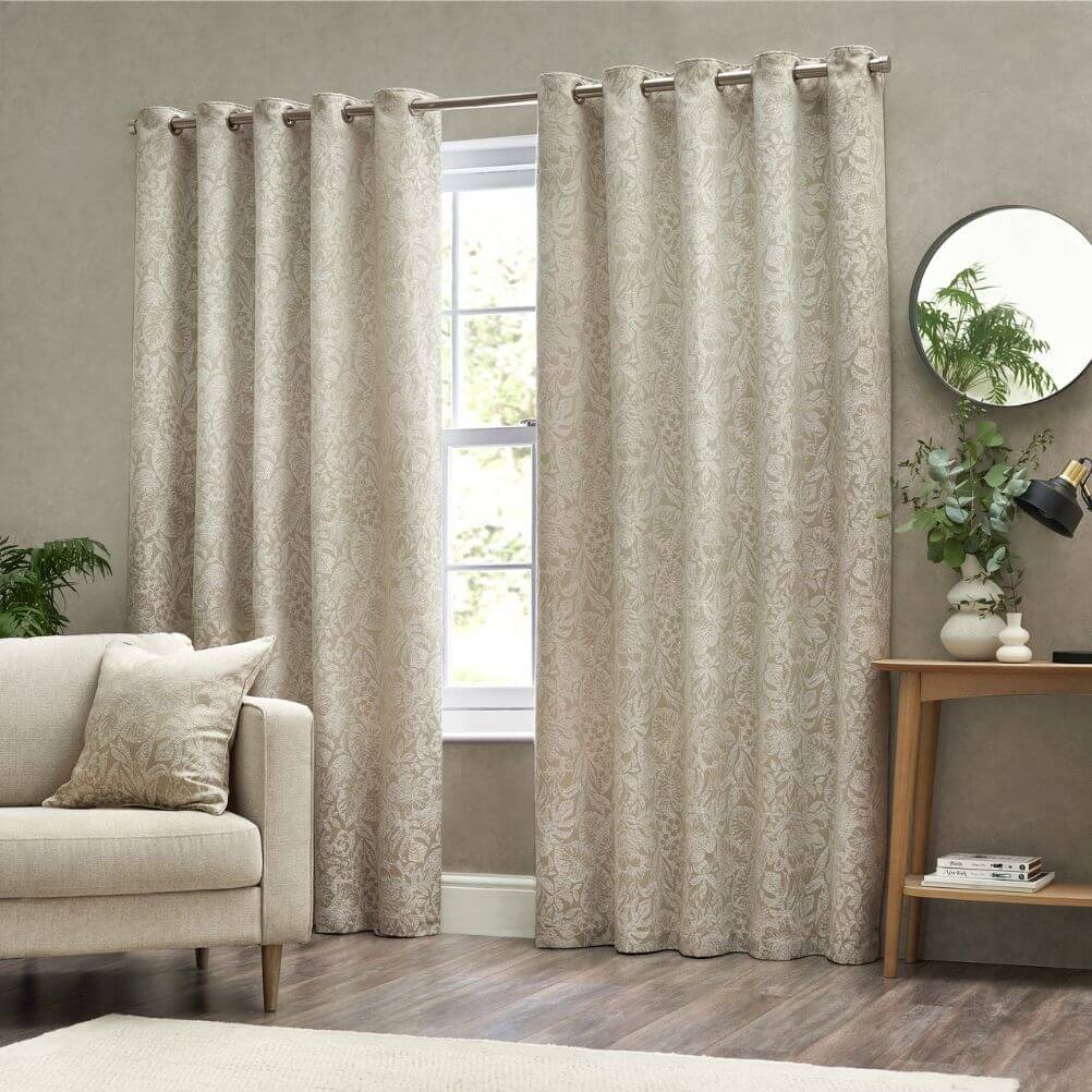 A neutral living room with natural colour drenching, including natural floral curtains and a matching throw cushion.