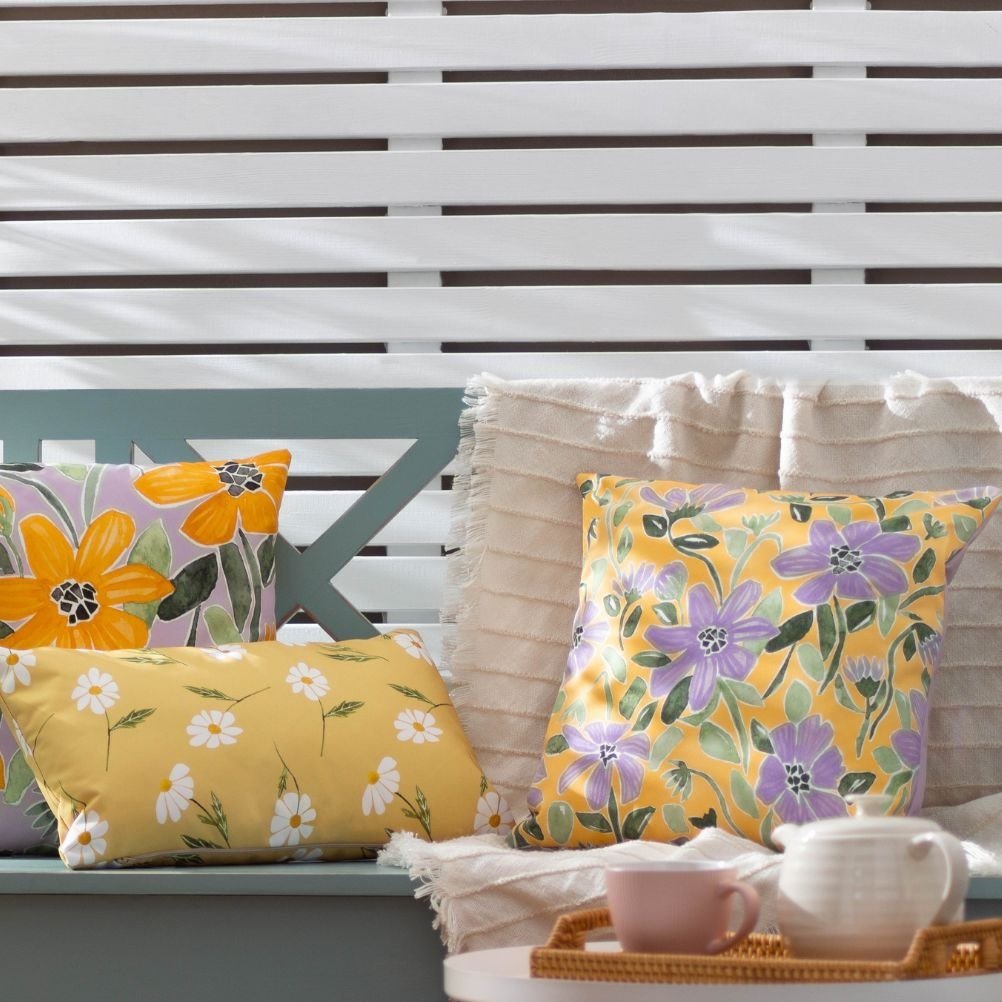 A selection of bright floral outdoor cushions arranged on garden furniture.