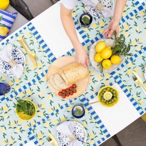 An outdoor entertaining area with a garden dinner party style, featuring outdoor table linen with a lemon design.