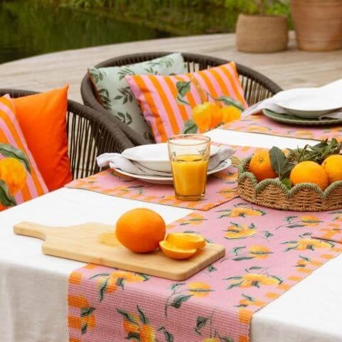 An outdoor entertaining area with a garden dinner party style, decorated with pink and orange outdoor table linen.