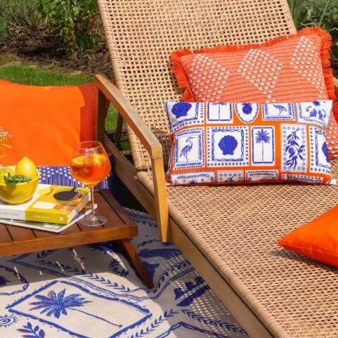 An outdoor entertaining area in a summer escape style, featuring a sun lounger, tropical outdoor cushions and an outdoor rug.