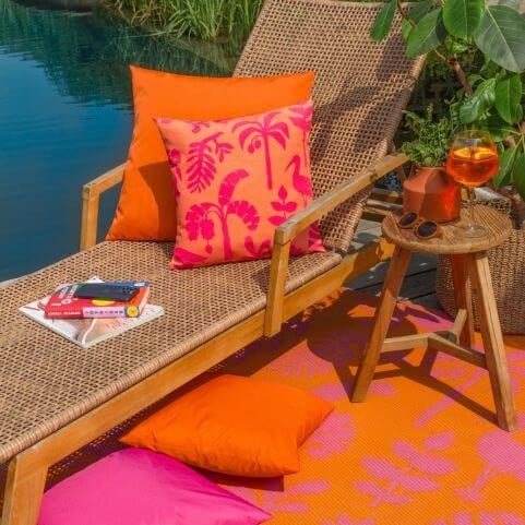 An outdoor entertaining area in a summer holiday style, featuring bright outdoor cushions and a tropical outdoor rug.