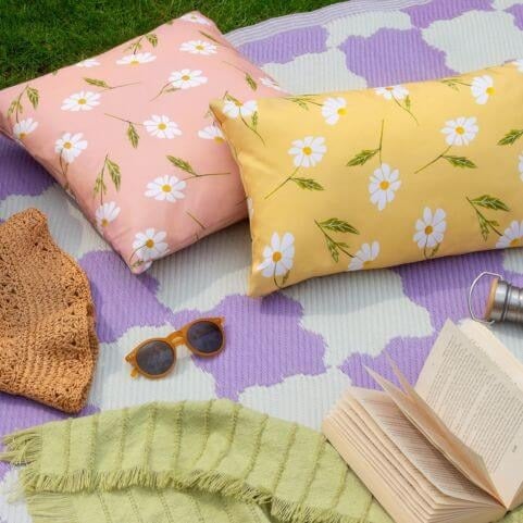 An outdoor entertaining area in a garden picnic style, featuring floral outdoor cushions and a weather-resistant outdoor rug.