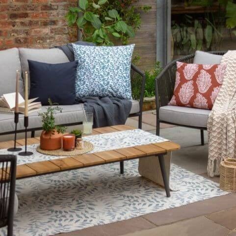 An outdoor entertaining area styled for quiet coffee mornings, featuring floral outdoor cushions, table linen and a matching outdoor rug.