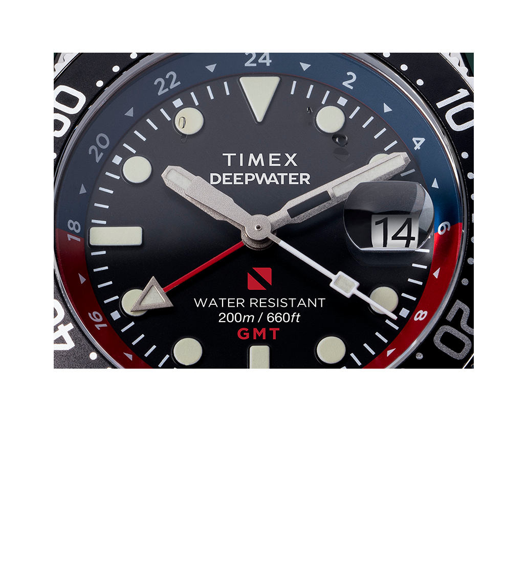 Detailed macro shot of the Timex Deepwater Reef 200 GMT dial, focusing on the red GMT hand, water resistance rating of 200m/660ft, and magnified date display.