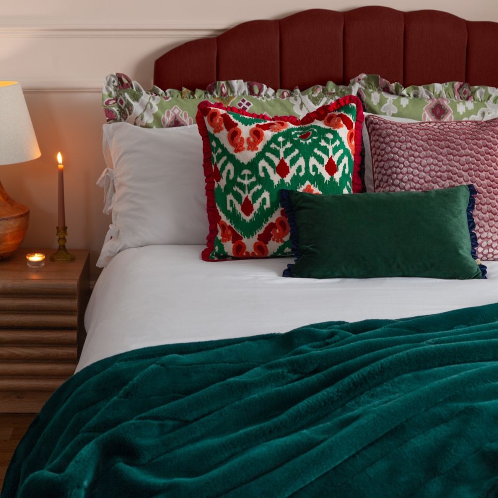A bed with colourful cushions and clashing patterns