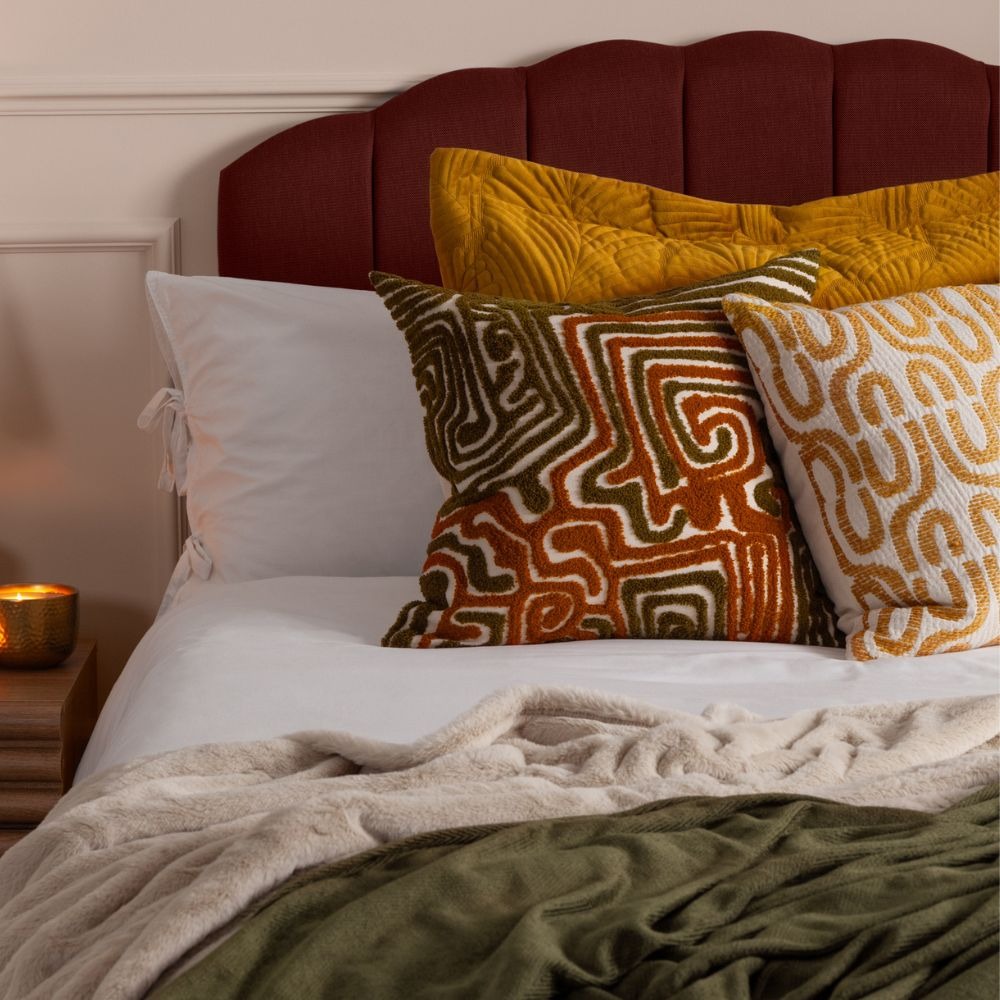 A pair of pattern clashing cushions with orange squiggles and a larger yellow cushion behind