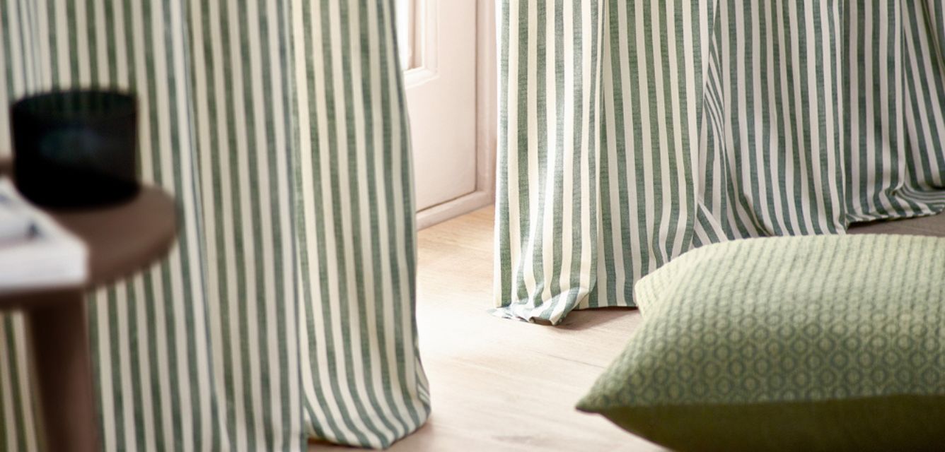 Striped curtains next to a cushion in a living room
